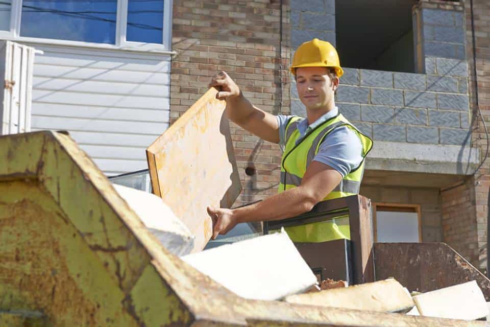 builder throwing away waste into a skip