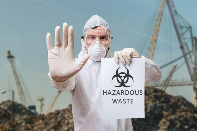 hazardous waste sign being held up by worker